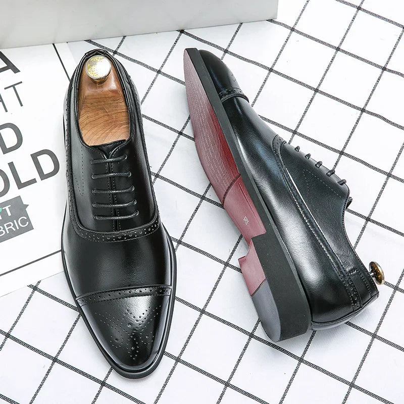 John Oxfordschoenen aan de voeten van een man in een zakelijke setting, zittend aan een bureau.