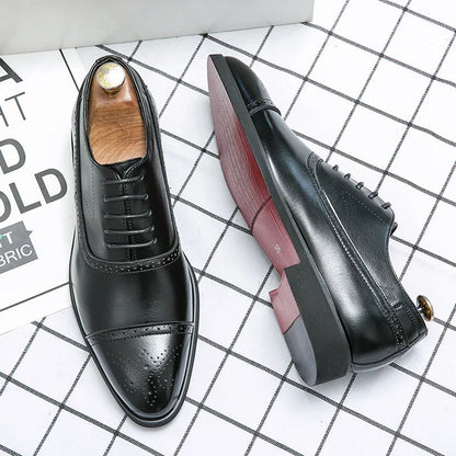 John Oxfordschoenen aan de voeten van een man in een zakelijke setting, zittend aan een bureau.