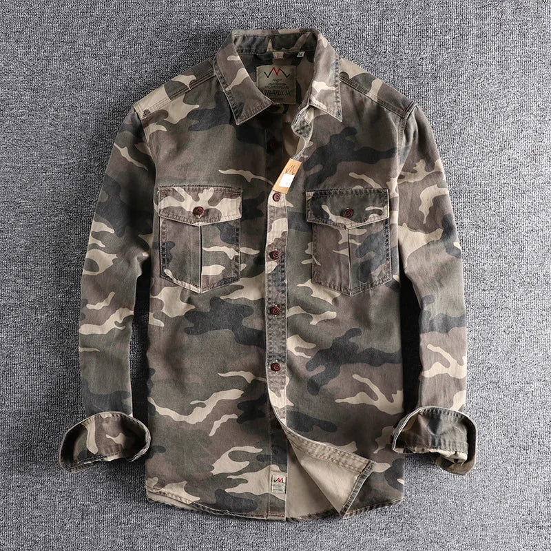 Detailopname van de stof van het camouflage T-shirt, waarbij de fijne textuur en het patroon goed zichtbaar zijn.