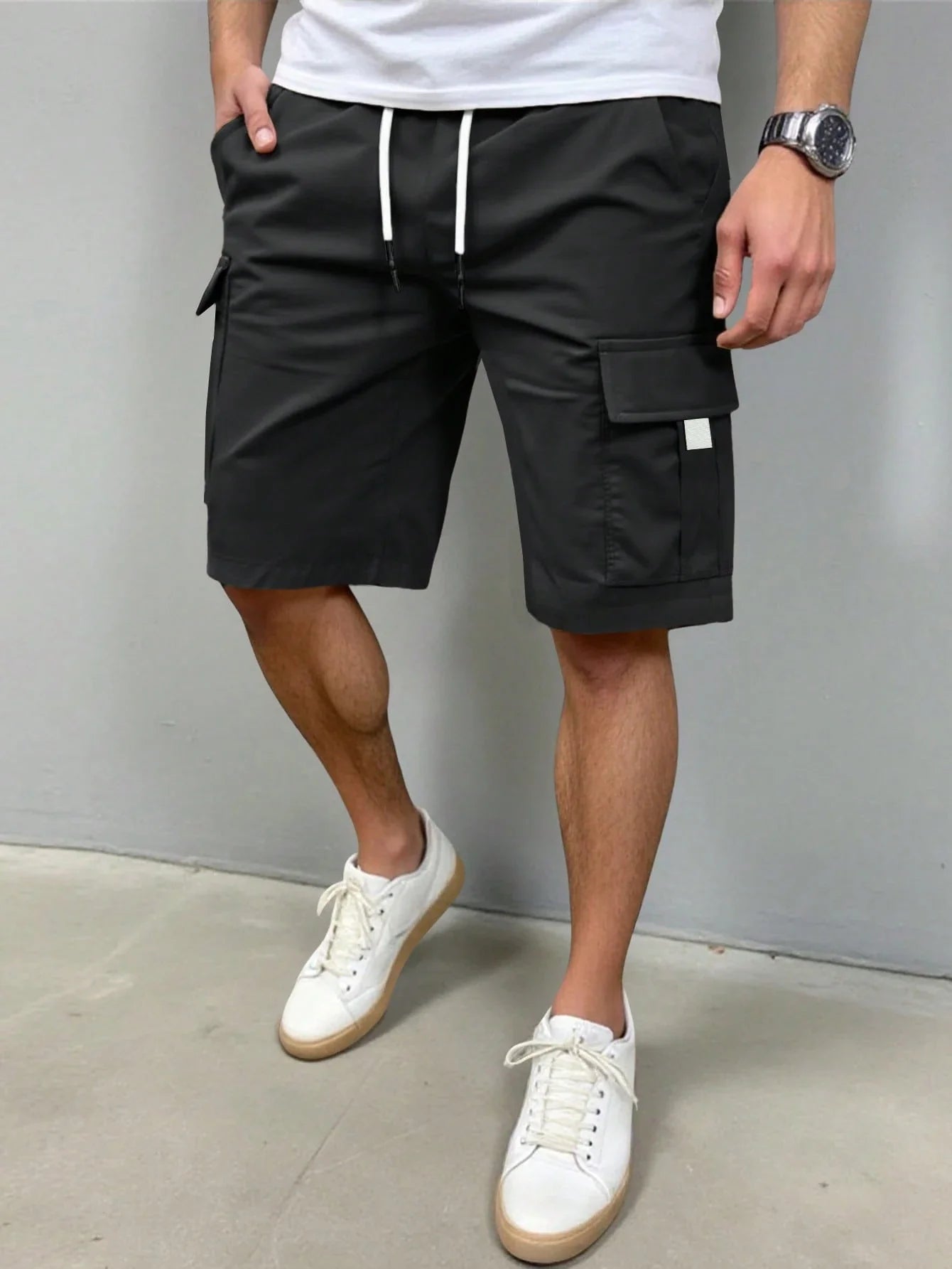 Detailopname van de sluiting van de grijze cargoshorts, inclusief knoop en rits.