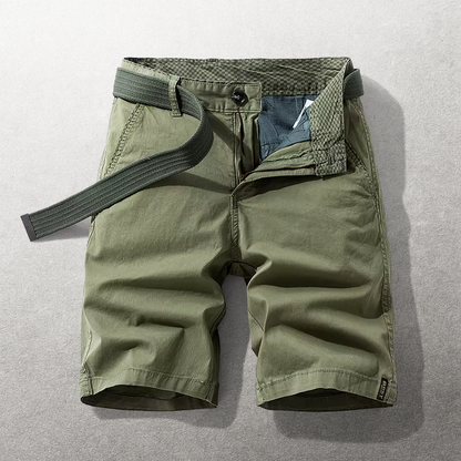 Zijaanzicht van een man die de groene Lennox katoenen chino shorts draagt, staand in een ontspannen houding.