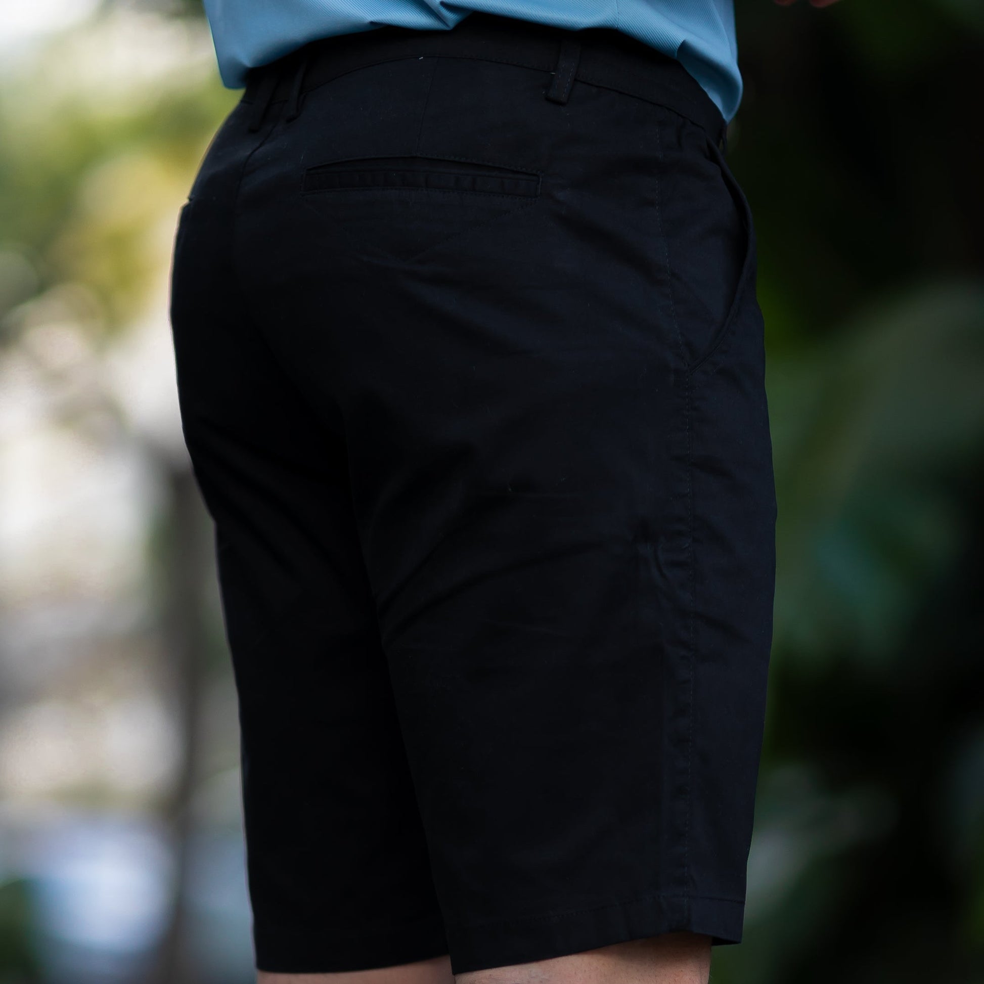 Een man leunt tegen een muur, gekleed in de Loris katoenen shorts, met een ontspannen en zelfverzekerde houding.