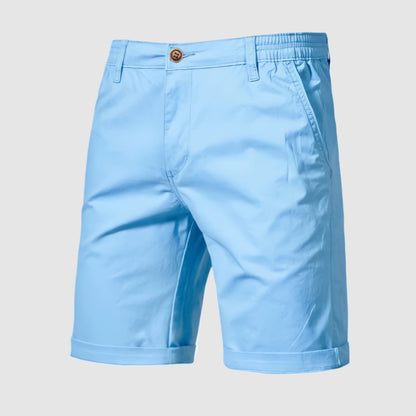 Een man staat bij een boot, gekleed in de Loris katoenen shorts, genietend van een zonnige dag.