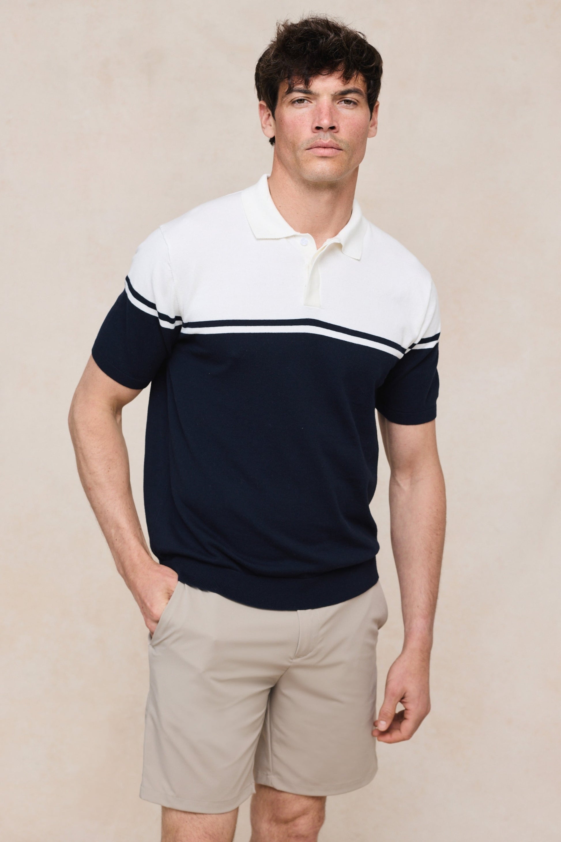 Achteraanzicht van het ecru en marineblauwe gebreide poloshirt, met aandacht voor de gestreepte patronen.