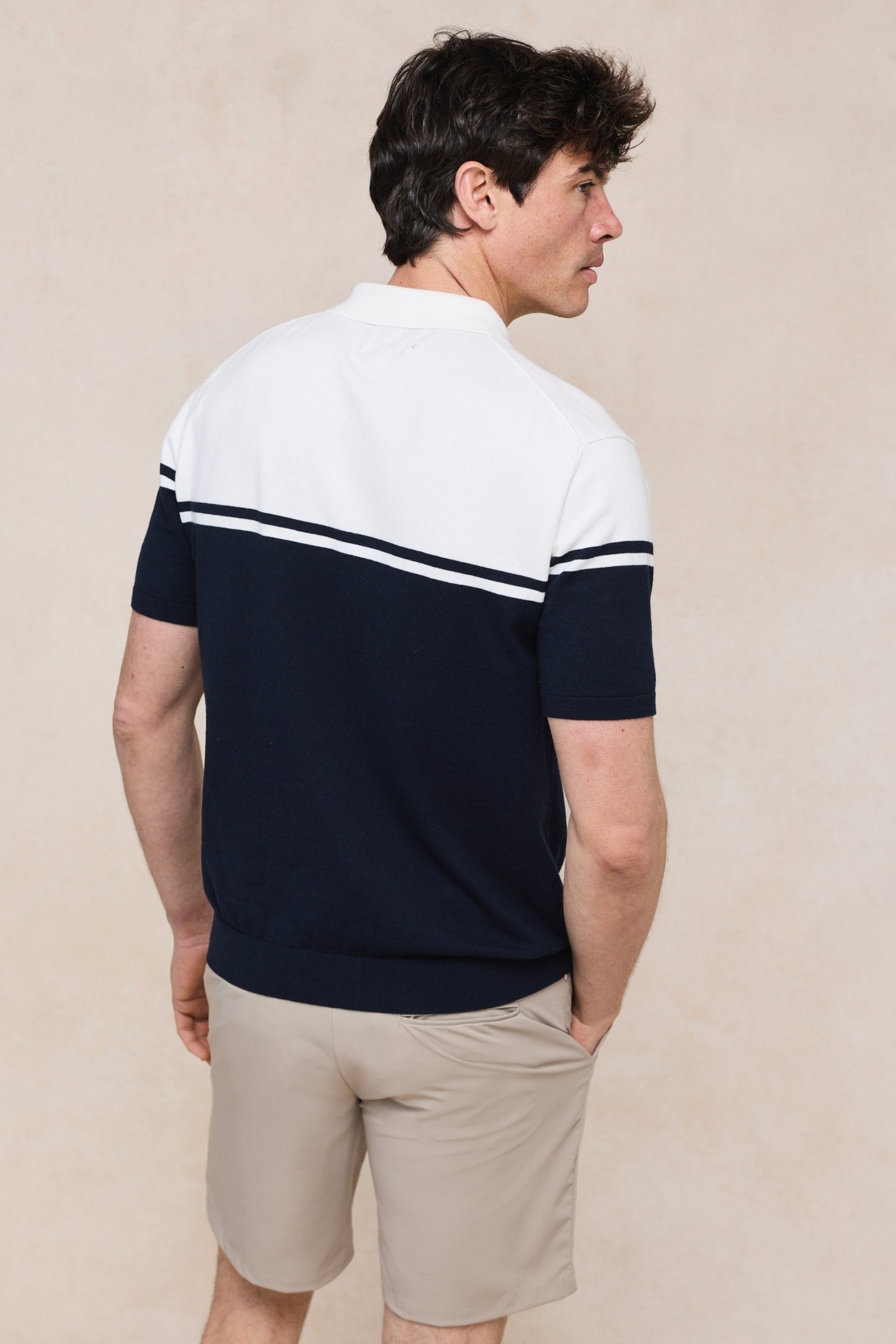 Het gebreide poloshirt plat gelegd op een lichte achtergrond, presenteert het complete kleurblokdesign.