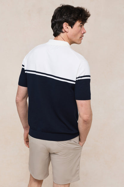 Het gebreide poloshirt plat gelegd op een lichte achtergrond, presenteert het complete kleurblokdesign.