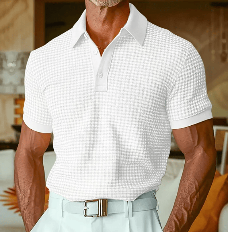 Man draagt het Nils poloshirt in een lichte tint, staand in een ontspannen buitenomgeving, casual gestyled.