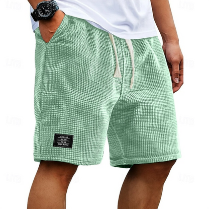 Achterkant van de beige wafelkatoenen shorts, met aandacht voor de relaxte pasvorm en de afwerking.