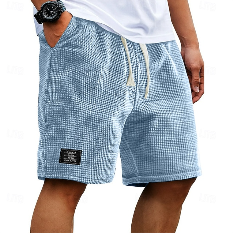 Close-up van de wafeltextuur op de stof van de beige shorts, die de ademende kwaliteit benadrukt.