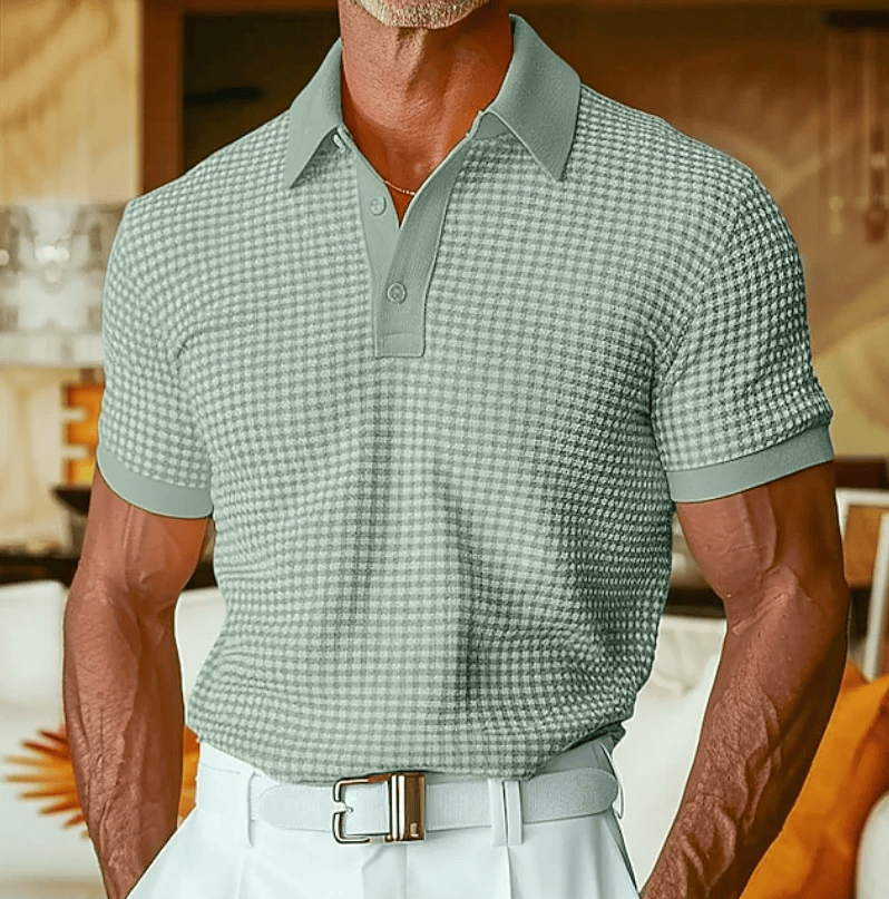 Nils poloshirt in een donkere kleur, gecombineerd met een chino, voor een smart-casual look, heldere belichting.