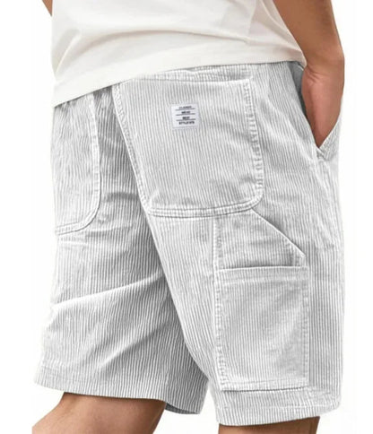 Man die de Remi cargoshort in lichtgroen draagt, leunend tegen een muur, met focus op de casual stijl.
