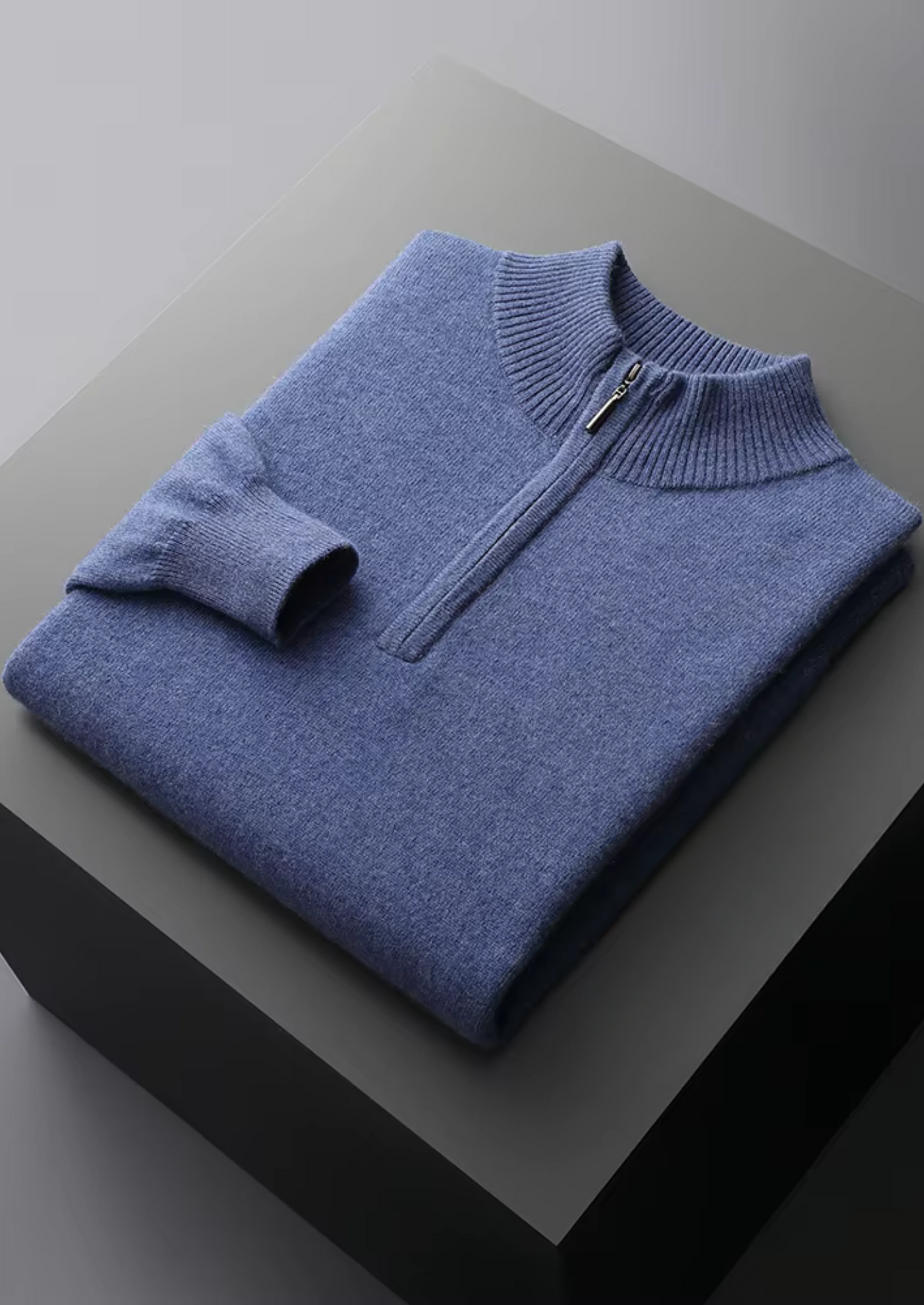 Detail van de mouwboord en zoom van de blauwe half-zip sweater, toont subtiele elasticiteit en afwerking.