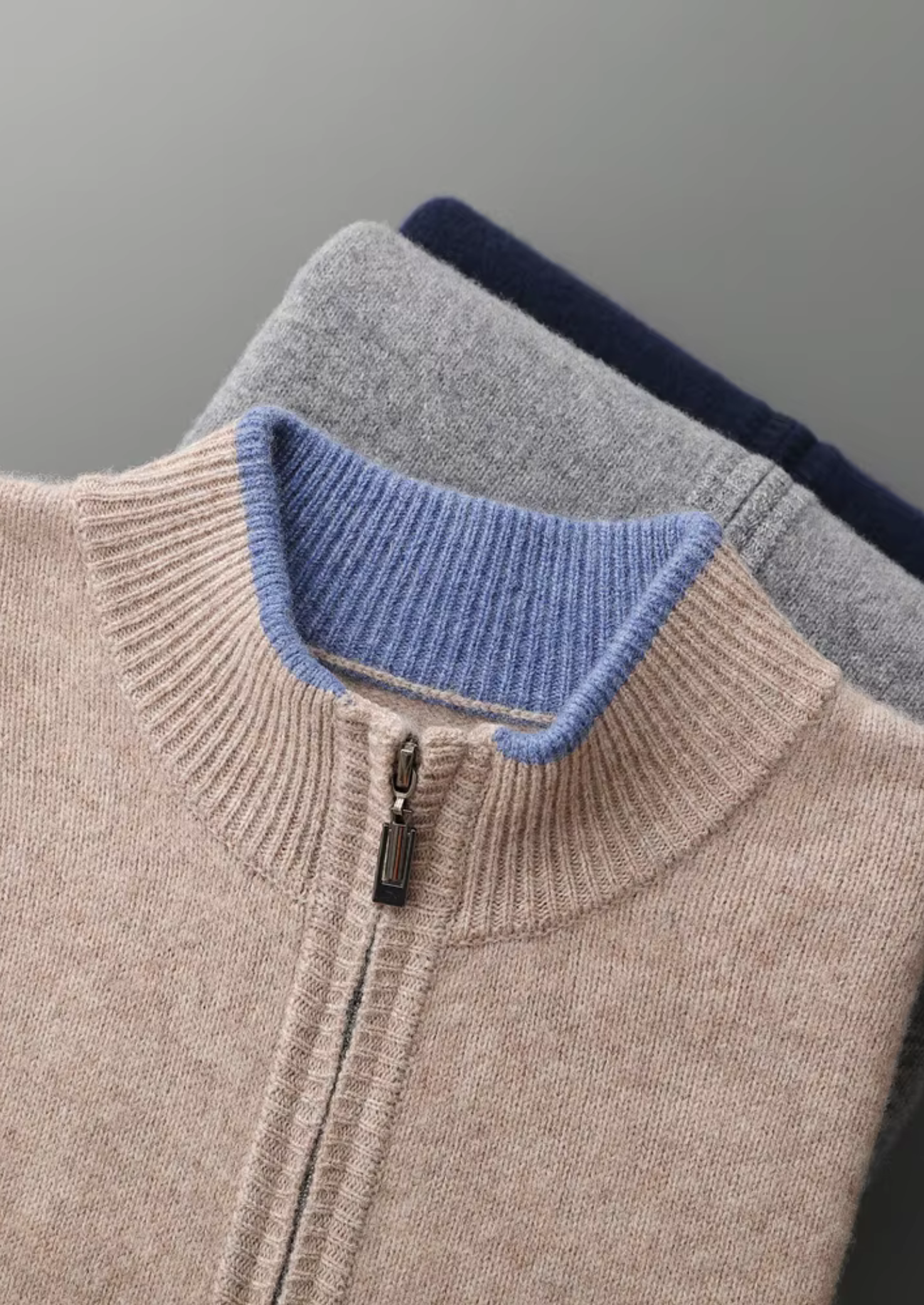 Stapel van drie cardigans in verschillende kleuren (grijs, beige, donkerblauw), toont kleuropties.