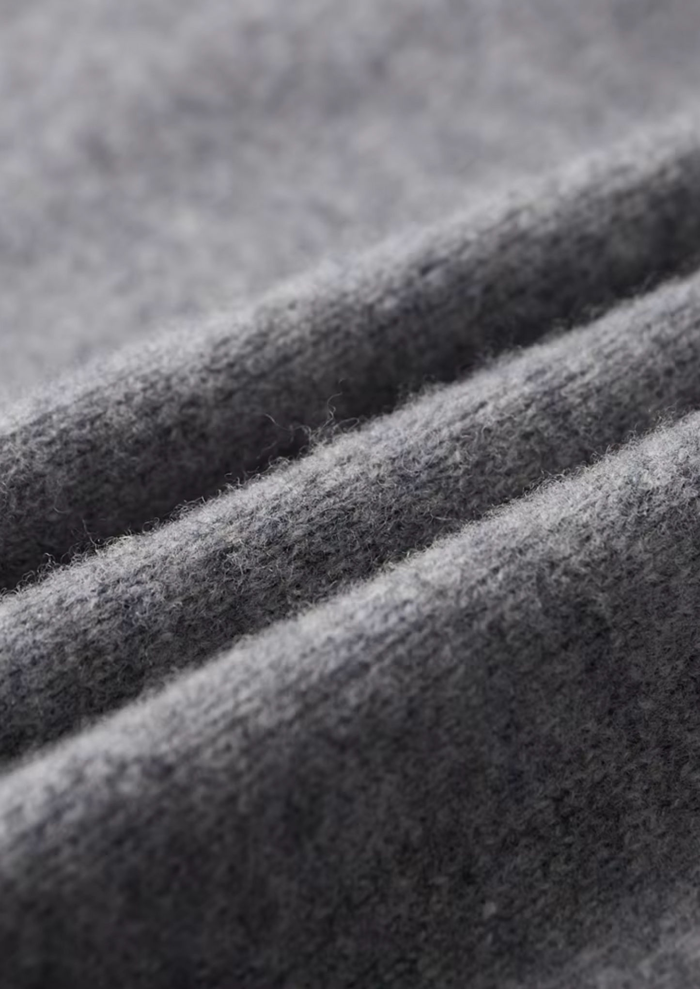 Close-up van de mouwboord en de naadloze afwerking van de beige cardigan.