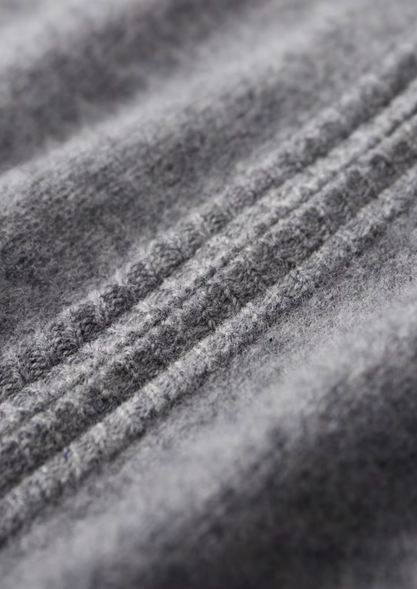Textuurdetail van de extra-fijne merinowol van de donkerblauwe cardigan, zacht en luxueus.