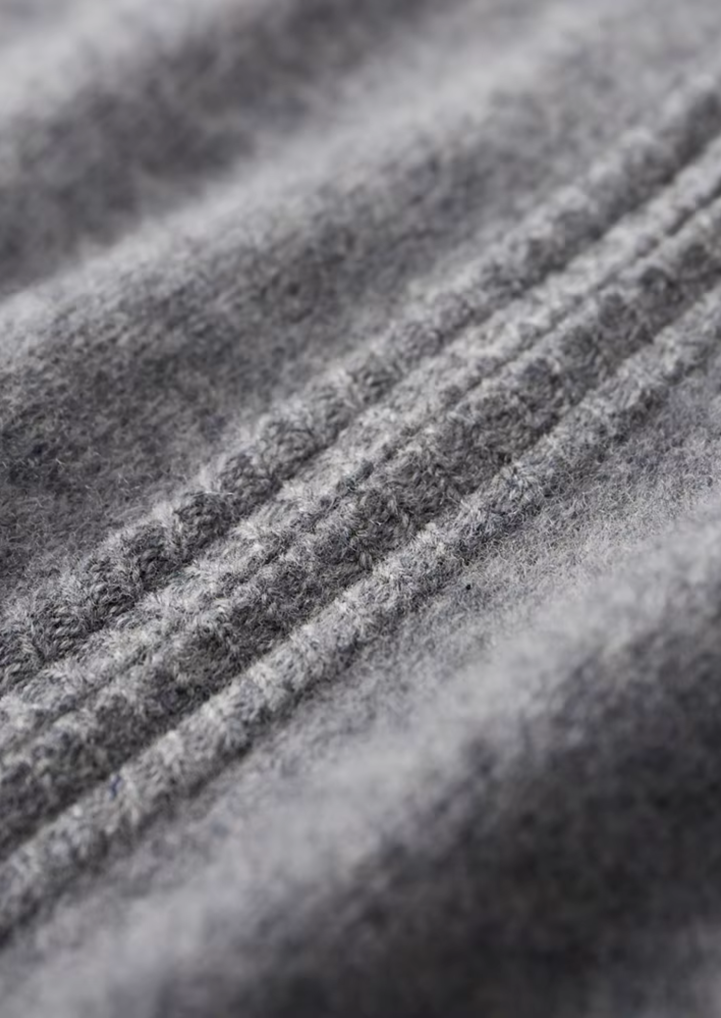 Textuurdetail van de extra-fijne merinowol van de donkerblauwe cardigan, zacht en luxueus.
