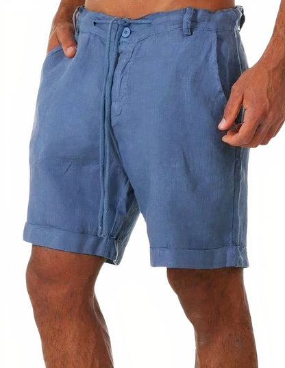 Zijaanzicht van een man die groene Reuben linnen shorts draagt, staand op een zonnig terras, casual gestyled.