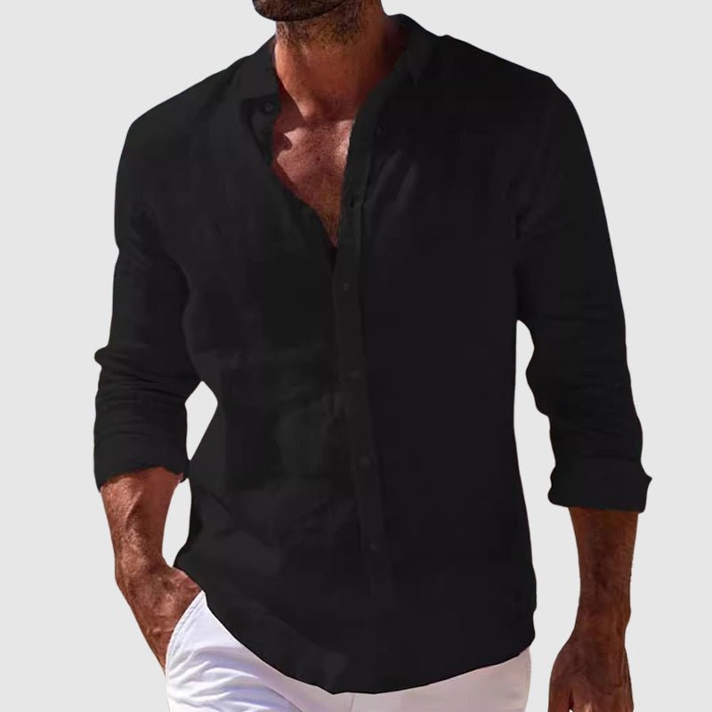 Een man draagt het witte Reuben linnen shirt casual, staand bij een zomerse setting