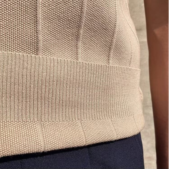 Een man poseert met het beige Reuben T-shirt, gecombineerd met een klassieke broek voor een complete look.