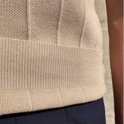 Een man poseert met het beige Reuben T-shirt, gecombineerd met een klassieke broek voor een complete look.