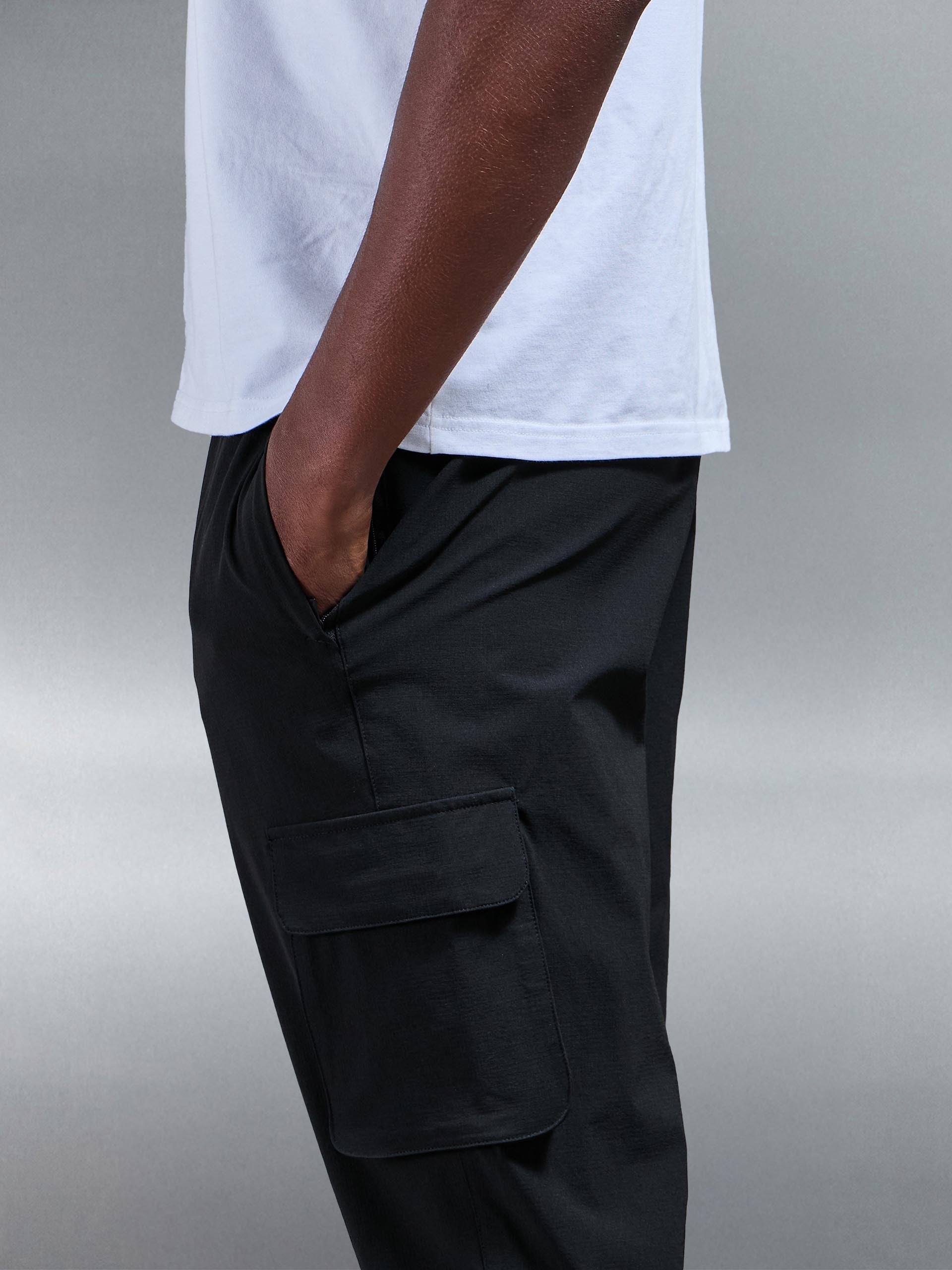 Model in actie, toont de bewegingsvrijheid van de zwarte heren cargo broek tijdens een casual wandeling.
