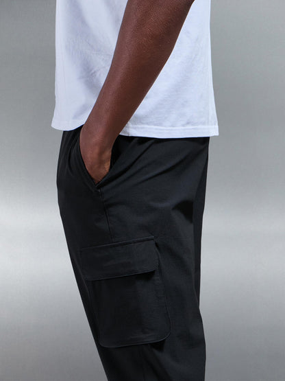 Model in actie, toont de bewegingsvrijheid van de zwarte heren cargo broek tijdens een casual wandeling.