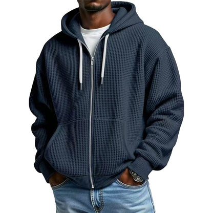Zijaanzicht van de blauwe wafelgebreide hoodie, toont de ruime capuchon en de lengte van het kledingstuk.