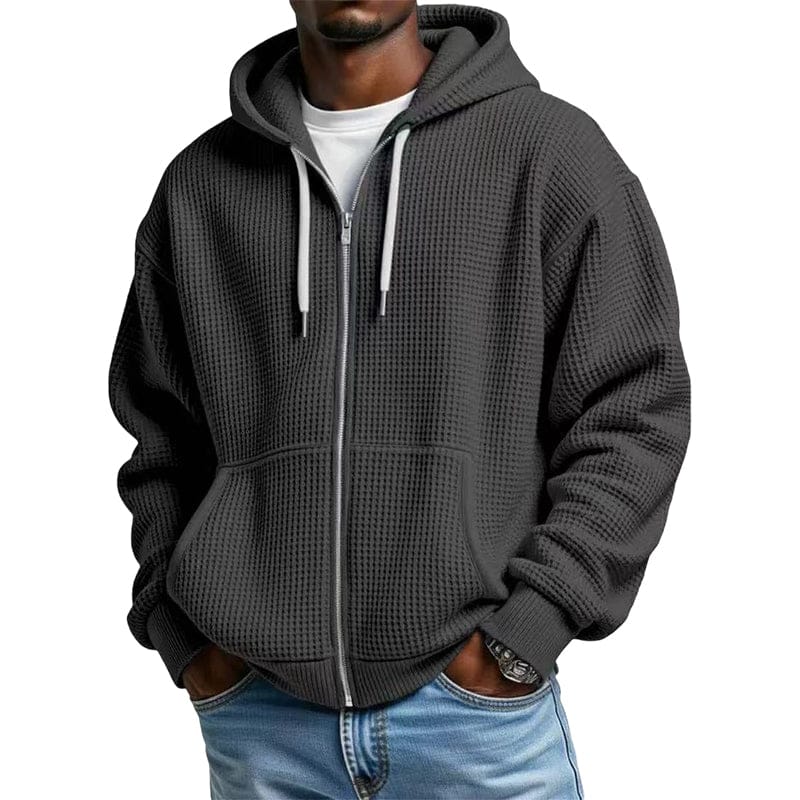 Een man draagt de Gerrit hoodie in grijs, zittend en lezend, wat de casual en relaxte pasvorm benadrukt.