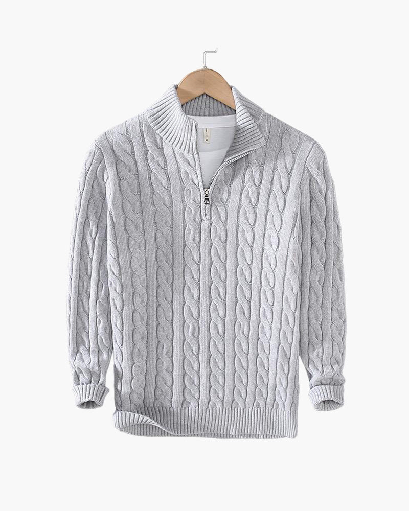 Close-up van de ribgebreide hoge kraag en de zilverkleurige half-zip ritssluiting van deze katoenen trui.