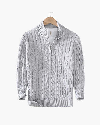 Close-up van de ribgebreide hoge kraag en de zilverkleurige half-zip ritssluiting van deze katoenen trui.