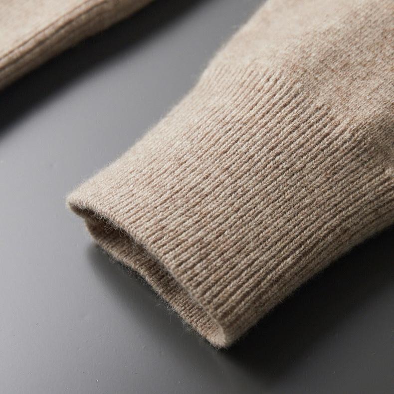 De olijfgroene Merino wollen trui hangend, waarbij de natuurlijke val en de elegante uitstraling zichtbaar zijn.